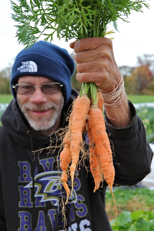 David Ruch posing with Red Wiggler carrots. 