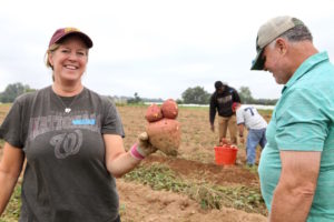 Board Member Katie Sebastian Leary posing with a sweet potato. 